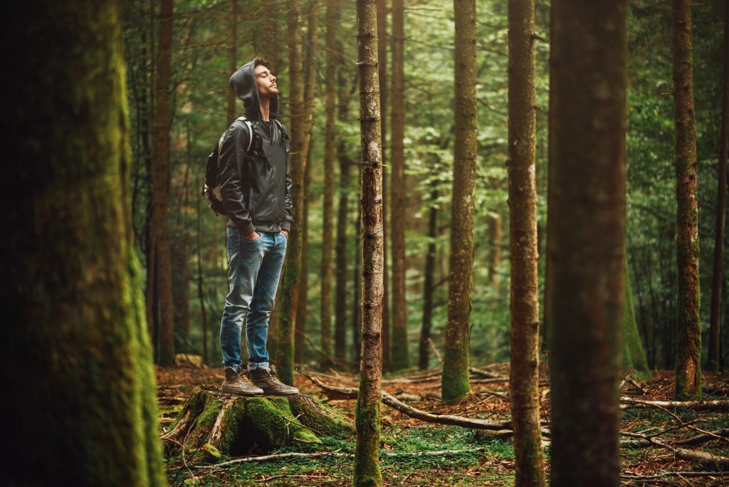 Mann mit Kapuze posiert im Wald